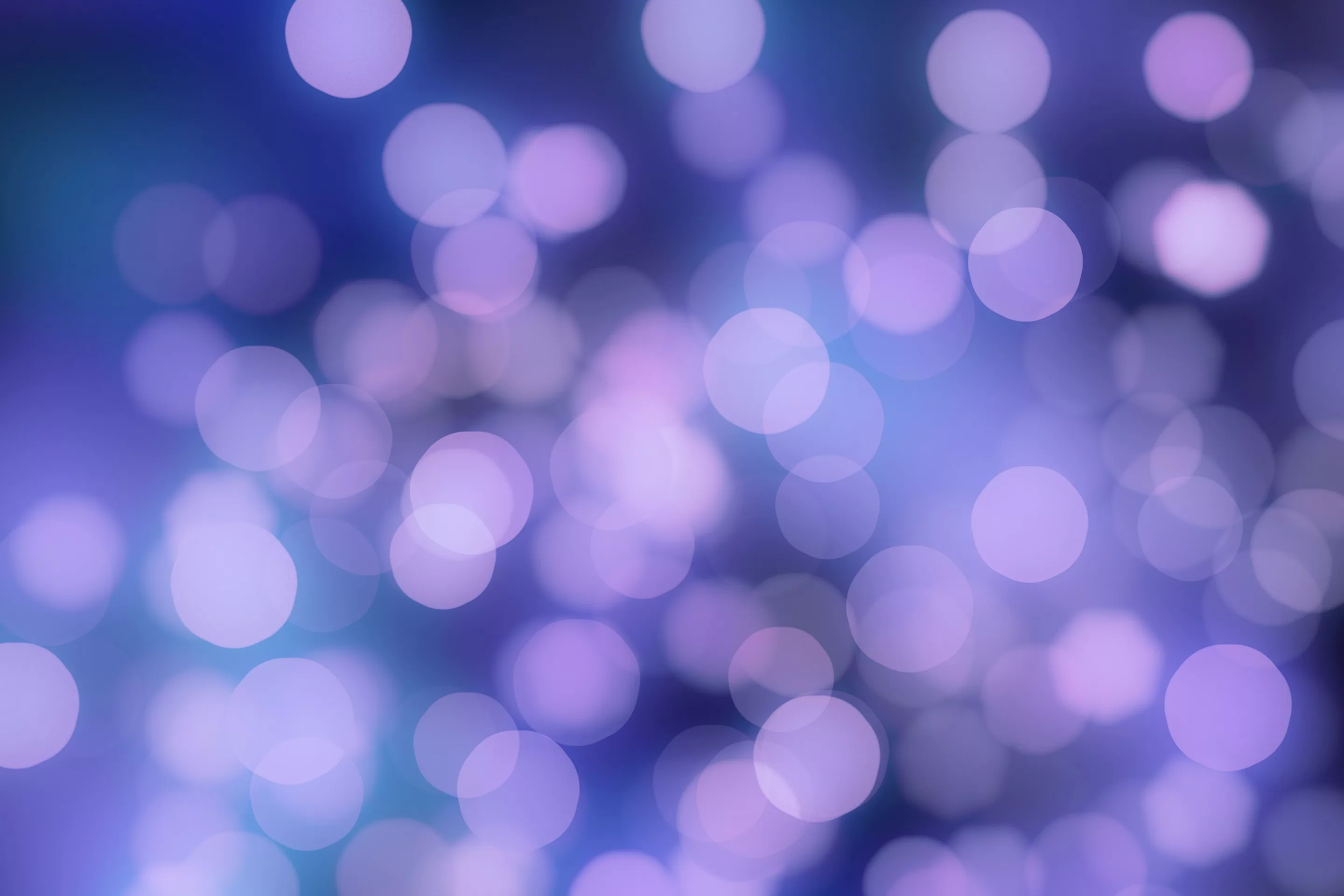 Unscharfer Hintergrund mit lila und blauen Lichtern, die einen weichen Effekt erzeugen. Die Kreise variieren in ihrer Größe und erzeugen eine verträumten Atmosphäre.